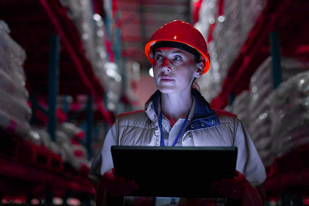 Logistics coordinator at a desk reviewing shipment records on screen