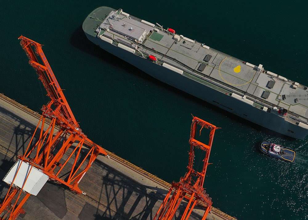 A roll-on roll-off vehicle carrier alongside a berth with its stern ramp lowered